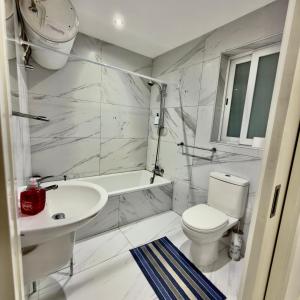 a white bathroom with a toilet and a sink at Sliema Seaview Apartment- Valletta Views - APT 8, 49 Tigne Point Mansions in Sliema