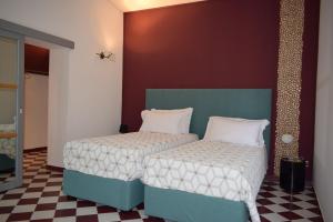 Dos camas en una habitación con paredes rojas y suelo ajedrezado. en Villa Francesca Luxury Rooms, en San Demetrio Corone