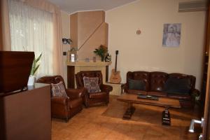 sala de estar con muebles de cuero y guitarra en Villa Francesca Luxury Rooms, en San Demetrio Corone