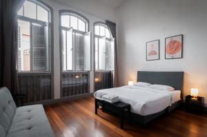 een slaapkamer met een bed, een bank en ramen bij Aayu Melayu - George Town Penang in George Town