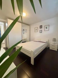 Un dormitorio con una cama blanca y una planta. en Betnava Apartment, en Maribor