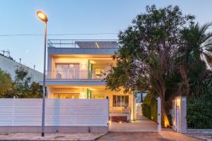 a house with a white fence and a tree at Luxury apartment Villa Vera Mondello beach with pool in Palermo