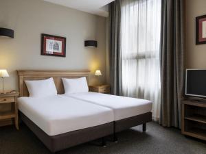 a hotel room with a bed and a television at Aparthotel Adagio La Défense Esplanade in Puteaux