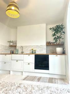 a kitchen with white cabinets and a black dishwasher at Entire Apartment in Pretty Coastal Village in Cubert