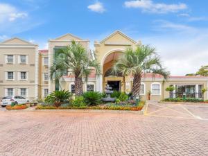 a large building with palm trees in front of it at Mercure Johannesburg Midrand in Midrand