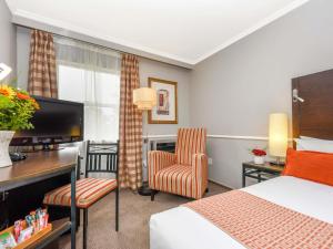 a hotel room with a bed and a desk with a computer at Mercure Johannesburg Midrand in Midrand +91 photos