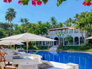 a pool at the resort with tables and umbrellas at DPNY Beach Hotel & SPA Ilhabela in Ilhabela