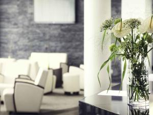 a vase of flowers sitting on a table with chairs at Mercure Hotel Lüdenscheid in Lüdenscheid