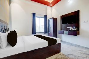 Un dormitorio con una cama grande y un televisor. en Hotel O Om Sai inn, en Prayagraj