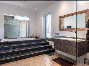 a bathroom with stairs and a tub and a mirror at Alpin Chalet ARTE in Söll +17 photos