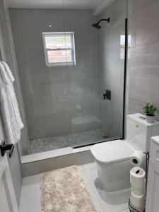 a white bathroom with a shower and a toilet at Adasie Palace in Saint Johnʼs