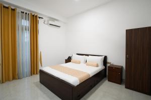 a bedroom with a large bed with yellow curtains at Die ChillOuz Pub & Lodge in Negombo
