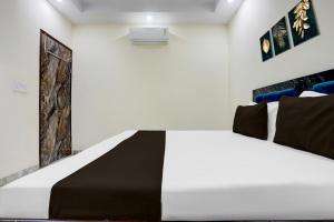 Dormitorio blanco con cama blanca y negra en Hotel O Apna Hotel, en Nueva Delhi