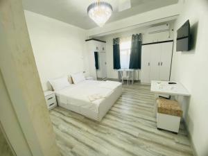 a white room with a bed and a desk and a tv at Mellinium apartment in old city in Bukhara