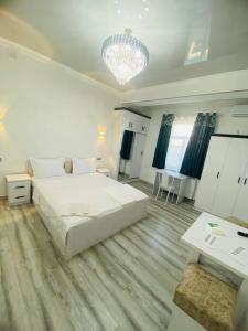 a bedroom with a large white bed and a chandelier at Mellinium apartment in old city in Bukhara