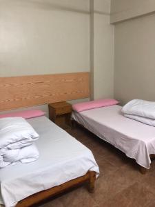 two beds in a room with white and pink sheets at Room in santa maria tower hy ell dollar in Marsa Matruh