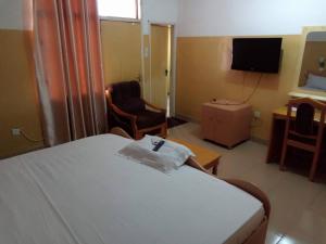 a hotel room with a bed and a chair and a television at Heritage Hotel in Trofwi