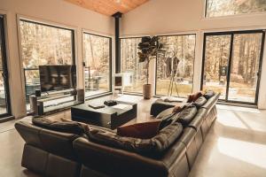 a living room with a leather couch and a television at Two Zen Houses - Villas and Spas in Morin Heights +14 photos