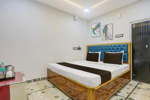 a bed with a blue headboard in a room at Hotel O The 4th Town in Jamshedpur