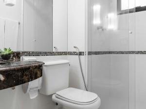 a white bathroom with a toilet and a shower at Mercure São Paulo Ibirapuera Privilege in São Paulo