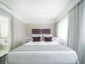 a bedroom with a large white bed with purple pillows at Mercure São Paulo Ibirapuera Privilege in São Paulo +143 photos