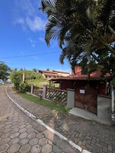 a building with a palm tree next to a street at Pousada Mandala em frente a Praia da Concha in Itacaré