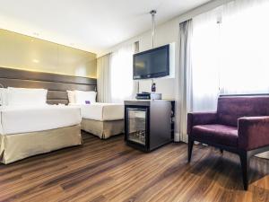 a hotel room with two beds and a tv and a chair at Mercure Sao Paulo Vila Olimpia in Sao Paulo +201 photos