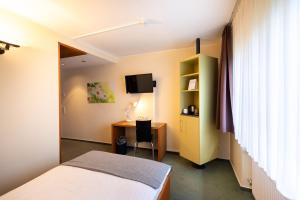 ケルンにあるGarner Hotel Cologne East by IHGのベッド、机、テレビのある寝室