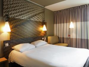 Una habitación de hotel con una cama grande y una silla. en ibis Paris La Defense Courbevoie, en Courbevoie