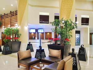 un hall avec des chaises et des plantes en pot dans un bâtiment dans l'établissement Novotel Cairo 6th Of October, à Ville du 6 Octobre