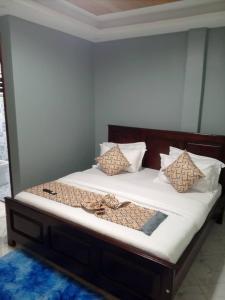 Una cama con almohadas en una habitación. en Ayeba Zion Hotel, en Fort Portal