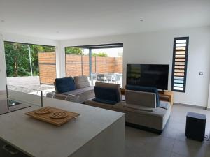 a living room with couches and a flat screen tv at Villa 4 étoiles Bon Air in Bouillante