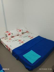a bed with a blue sheet and flowers on it at D-Bayu Motel in Papar