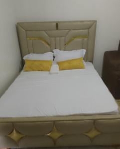 a large bed with two yellow pillows on it at Prift Royal Apartments in Meru