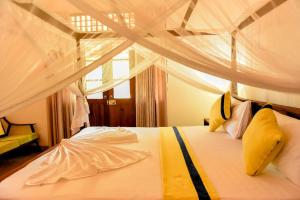 1 dormitorio con cama blanca con dosel y almohadas amarillas en The Ehela, en Tangalle