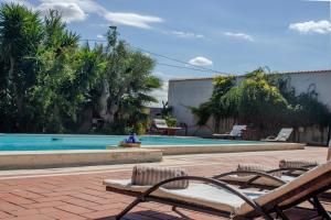 a swimming pool with chairs next to a resort at La Serra - Villa De Bonis in San Cesario di Lecce
