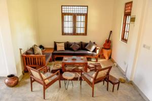 una sala de estar con un sofá, una mesa y sillas en The Ehela, en Tangalle