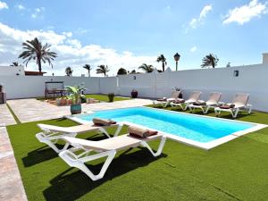 a backyard with a pool and lounge chairs and a swimming pool at The Suite Villa in Playa Blanca