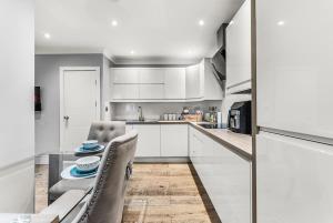 a kitchen with white cabinets and a table and chairs at Beautiful 2 Bedroom Home In Bristol in Bristol