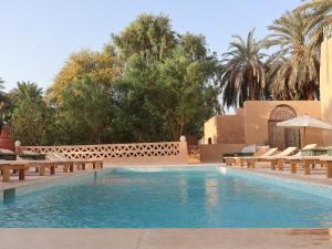 a swimming pool in a resort with benches and trees at Habu Hotel in Al Aqālitah +43 photos