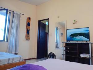 a bedroom with a tv and a bed and a mirror at Casa das Gaúchas in Canoa Quebrada
