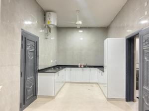 an empty kitchen with white cabinets and a door at إطلالة غروب الشمس in Misfāh