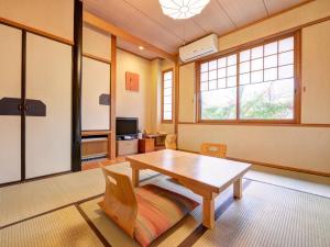 a living room with a wooden table and chairs at Yufuin Yamaboushi in Yufu