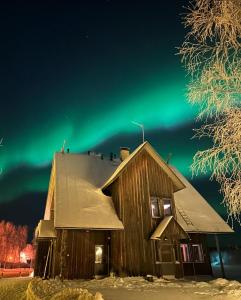 uma cabana antiga com a aurora boreal verde no céu em Shaman Village - Resort & Glass Igloos em Rovaniemi mais 28 fotografias