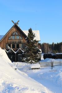 un granero cubierto de nieve con un árbol de Navidad delante en Shaman Village - Resort & Glass Igloos, en Rovaniemi
