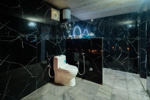 a bathroom with a toilet and a black wall at Dunes Heritage Desert Camp in Jaisalmer