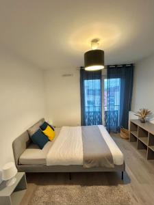 a bedroom with a bed and a couch and windows at Superbe appart design - Rooftop privé proche Paris in Neuilly-sur-Marne