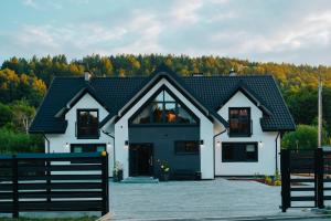 a white house with a black roof at Althea Ustrzyki Apartmants in Skorka