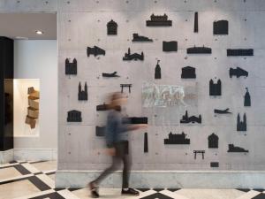 a person walking past a wall with art on it at Mercure Sao Paulo Bela Vista in Sao Paulo