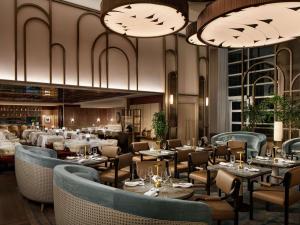 a restaurant with tables and chairs and chandeliers at Sofitel Montreal Golden Mile in Montréal